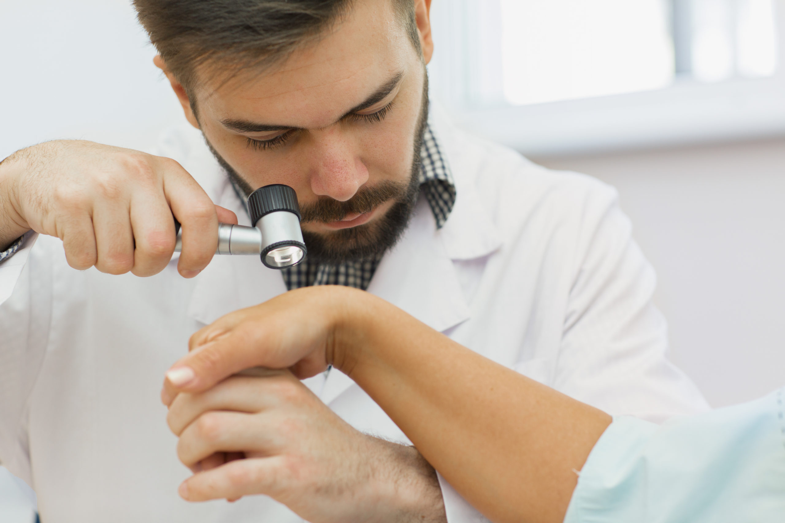 Professional dermatologist examining birthmarks and moles of a p